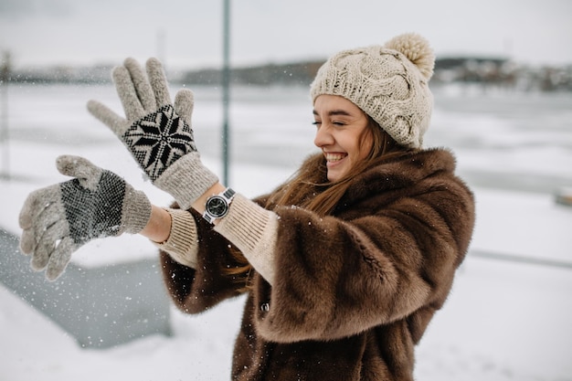 Ritratto invernale di bella donna sorridente con i fiocchi di neve