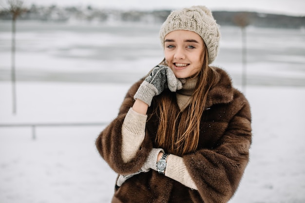 Ritratto invernale di bella donna sorridente con i fiocchi di neve