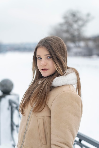 Ritratto invernale di bella ragazza in pelliccia bianca alla moda cappotto di pelle di pecora beige Giovane donna in tuta sportiva alla moda sulla passeggiata