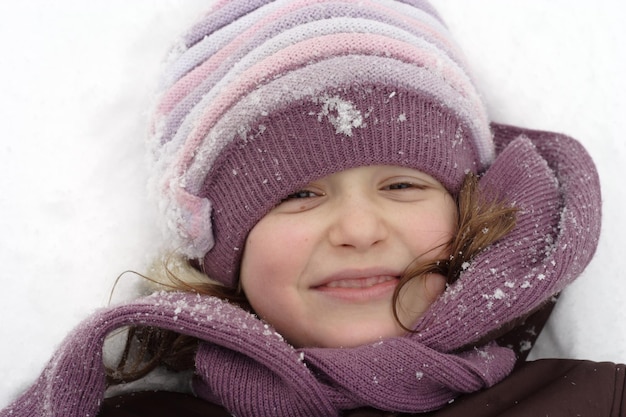 Ritratto invernale di ragazza sorridente con berretto coperto di neve