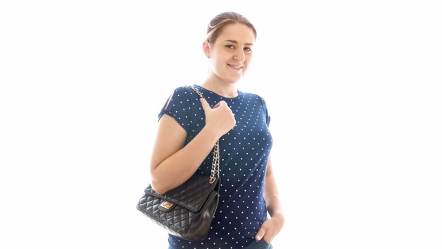 Ritratto isolato della donna adulta sorridente con la borsa nera che guarda a porte chiuse.