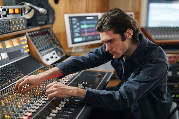 Ritratto laterale del produttore musicale che utilizza una workstation audio digitale in uno studio di registrazione professionale