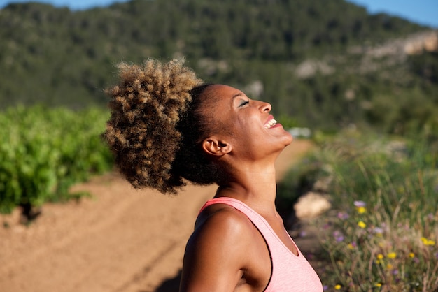 Ritratto laterale di giovane donna africana in buona salute che ride all&#39;aperto nella mattina