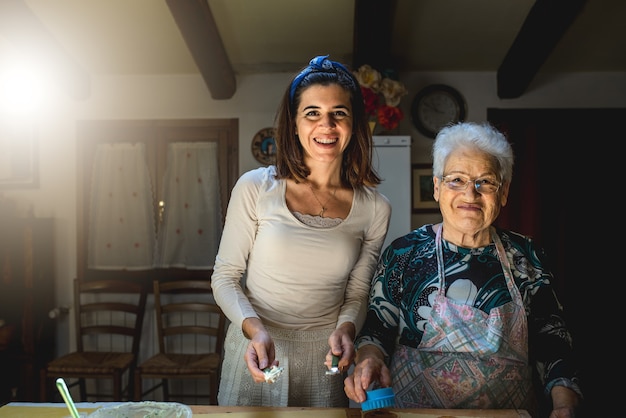 Ritratto nipote e nonna felici di trascorrere del tempo insieme a casa durante la quarantena. Preparare cibo tradizionale come pasta fatta a mano.