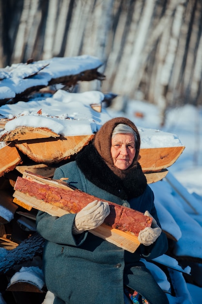 Ritratto Nonna russa, nel villaggio in inverno, a preparare legna da ardere, in Siberia.