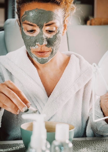 Ritratto primo piano di una bella donna adulta con maschera crema antietà per il trattamento della pelle. Persone di sesso femminile che hanno cura e uno stile di vita sano di bellezza. Prodotti naturali fatti a mano