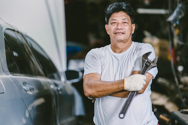 Ritratto professionale meccanico maschio asiatico sorriso felice uomo di lavoro nel servizio auto garage