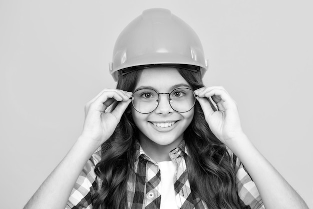 Ritratto ravvicinato del costruttore di bambini adolescente nel casco Ragazza adolescente sul lavoro di riparazione isolato su sfondo giallo