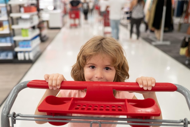 Ritratto ravvicinato di bambino con carrello acquisto di cibo in un negozio di alimentari Famiglia di clienti che acquistano prodotti al supermercato Faccia di bambini divertenti