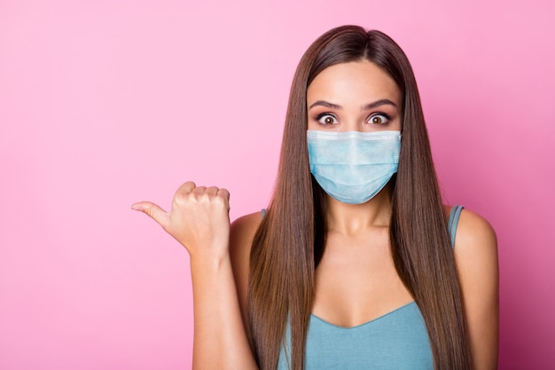 Ritratto ravvicinato di lei, lei, bella, attraente, adorabile, stupita, dai capelli lunghi, ragazza, indossando la maschera di sicurezza, dimostrando lo spazio della copia, fermare la prevenzione dell'influenza mers cov, isolato sfondo di colore rosa