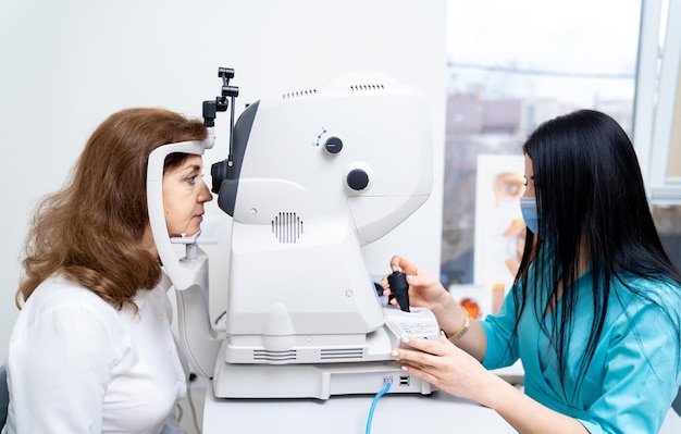 Ritratto ravvicinato di optometrista femminile che utilizza una macchina rifrattometrica durante il test della visione Paziente femminile in clinica Vita in su