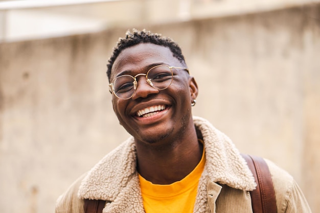 Ritratto ravvicinato di un adolescente afroamericano che guarda l'obbiettivo sorridente ridendo dell'università