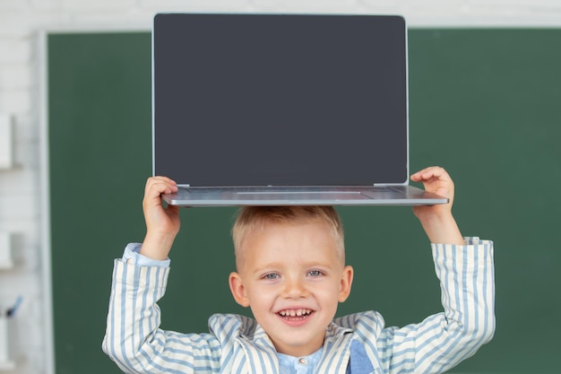 Ritratto ravvicinato di un bambino che tiene un computer portatile sulla testa per studiare l'educazione informatica per i bambini