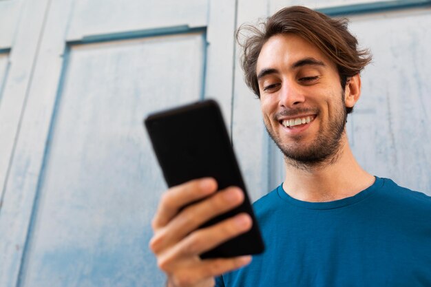 Ritratto ravvicinato di un giovane uomo caucasico sorridente che usa il telefono cellulare all'aperto Spazio di copia Messa a fuoco selettiva sul viso Concetto di stile di vita e social media