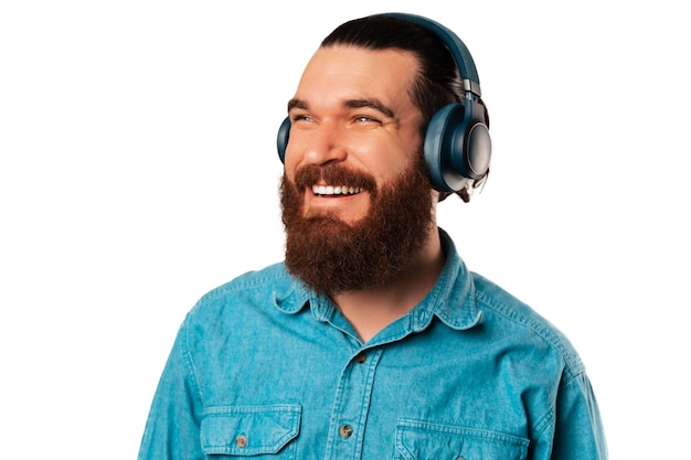 Ritratto ravvicinato di un uomo barbuto che ascolta musica o un audiolibro in cuffia