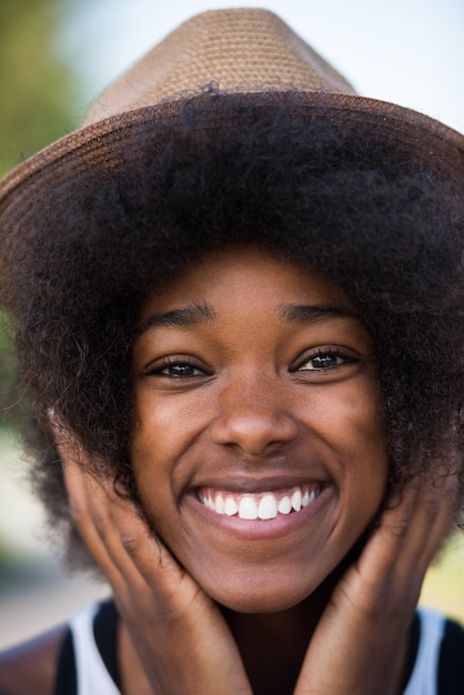 Ritratto ravvicinato di una bella giovane donna afroamericana sorridente e alzando lo sguardo in una bella giornata di sole