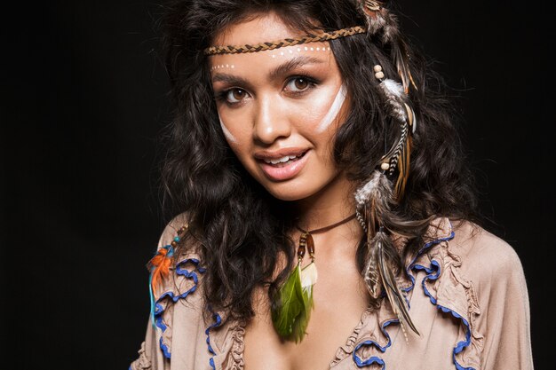 Ritratto ravvicinato di una bella giovane donna bruna sorridente che indossa abiti e accessori tribali in piedi isolati