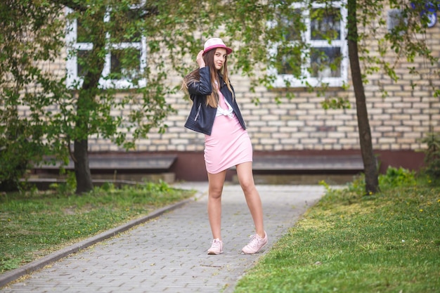 Ritratto ravvicinato di una bella ragazza alla moda con cappello vicino a un edificio in mattoni in una strada urbana come sfondo