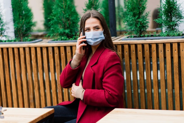 Ritratto ravvicinato di una donna caucasica che indossa una maschera medica e in piedi per strada e caffè