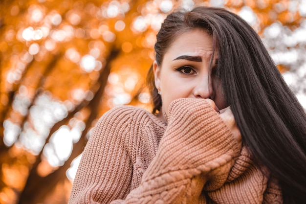 Ritratto ravvicinato di una donna in piedi nella foresta del parco cittadino autunnale, che si congela a freddo