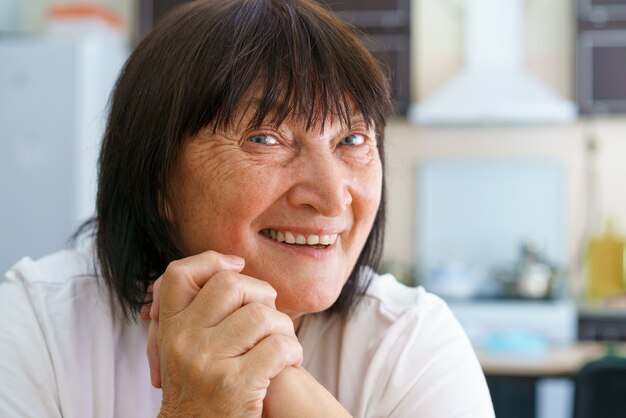 Ritratto ravvicinato di una donna matura sorridente seduta su un comodo divano a casa in posa per una foto felice co...