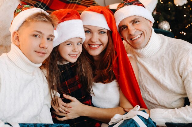 Ritratto ravvicinato di una famiglia felice seduta su un divano vicino a un albero di Natale che celebra una vacanza