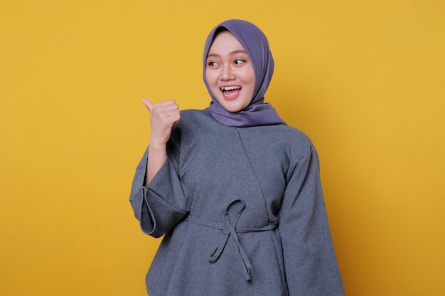 Ritratto ravvicinato di una giovane donna asiatica felice che indossa l'hijab che mostra il gesto del pollice in su