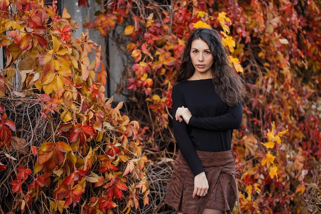 Ritratto ravvicinato di una giovane donna bruna sullo sfondo di un paesaggio autunnale bordeaux