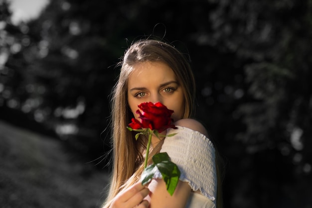 Ritratto ravvicinato di una giovane donna con in mano una rosa rossa