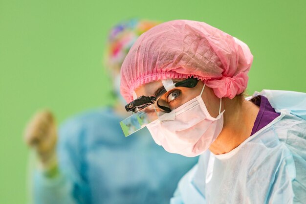 Ritratto ravvicinato di una giovane dottoressa chirurgo che indossa maschera e cappello protettivi durante l'operazione Concetto di chirurgia del servizio medico di emergenza di educazione medica sanitaria