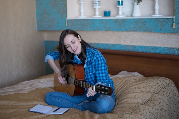 Ritratto reale di una giovane donna che impara a suonare la chitarra acustica. il concetto di creatività