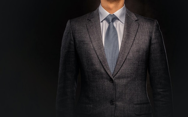 Ritratto ritagliato di un uomo d'affari di successo vestito con un elegante abito formale. Isolato su uno sfondo scuro.