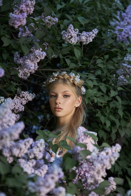 Ritratto romantico di una ragazza in natura in primo piano fiori lilla. Cosmetici naturali. Bellezza naturale di una donna in abito bianco