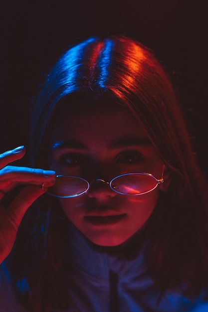 Ritratto stilizzato di una giovane ragazza con occhiali moderni che utilizza 2 fonti di luce colorata
