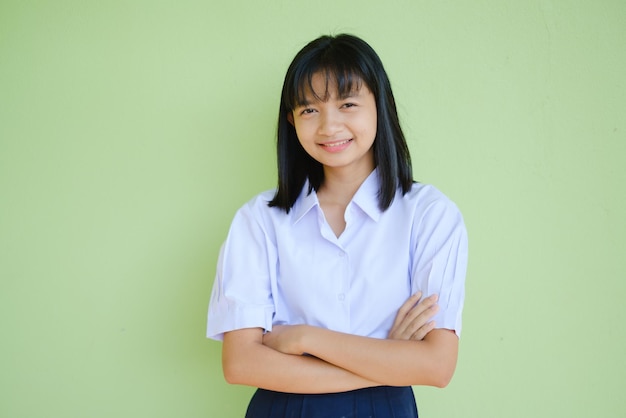 Ritratto studentessa giovane a scuola uniforme su sfondo verde, ragazza asiatica, adolescente.