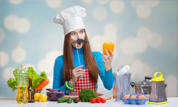 Ritratto umoristico di una donna in cappello da cuoco con baffi di carta guardando il pepe in mano