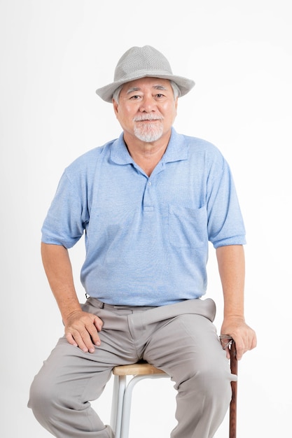 Ritratto uomo anziano asiatico, vecchio, sentirsi felice in buona salute indossando un cappello e tenendo un bastone da passeggio isolato su sfondo bianco - concetto di stile di vita maschio anziano