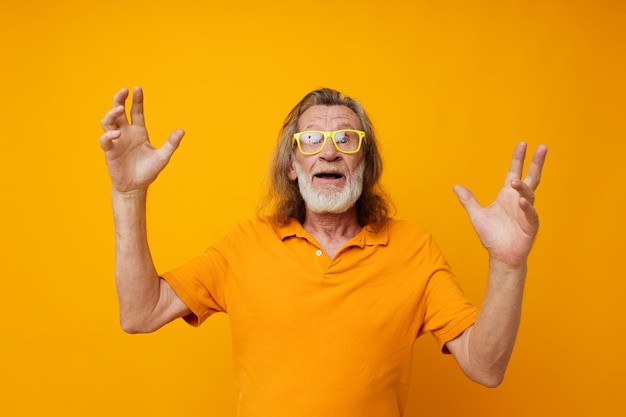 Ritratto uomo anziano giallo t-shirt e occhiali in posa sfondo isolato. Foto di alta qualità