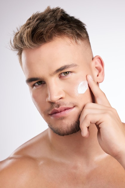 Ritratto uomo e crema per la cura della pelle per il viso per la bellezza della luce facciale e la salute della pelle per la lucentezza naturale in studio Per la persona maschile dermatologia e crema solare con benefici anti-invecchiamento su sfondo bianco