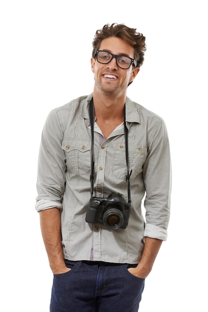 Ritratto uomo e fotografo con la telecamera al collo in studio isolato su uno sfondo bianco persona felice in occhiali creativi paparazzi e moda di modello sicuro con le mani in tasca in Spagna