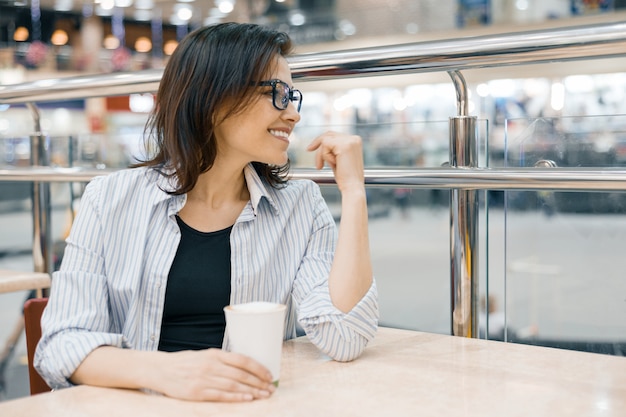 Ritratto urbano di donna che indossa occhiali con una tazza di caffè