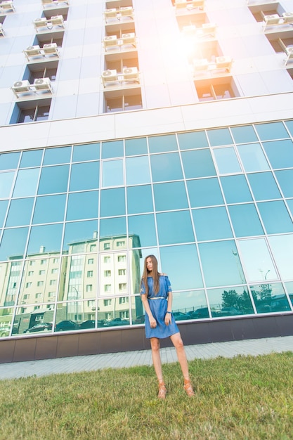 Ritratto urbano di moda di bella modella per strada. Giovane donna magra che indossa abito blu in città.