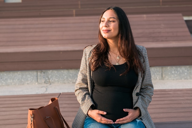 Ritratto urbano di una moderna donna latina incinta. Gravidanza e concetto di genitorialità.