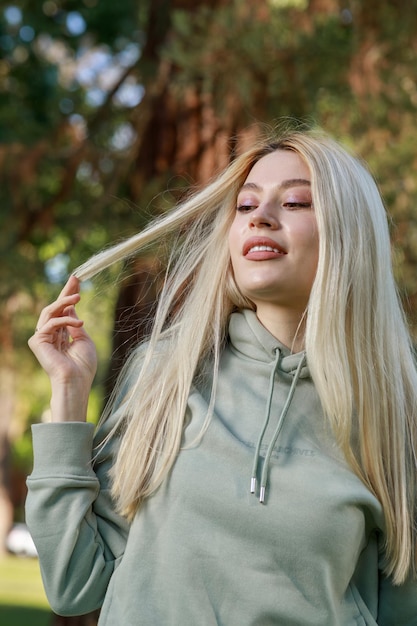 Ritratto verticale di giovane signora carina che allunga i capelli al parco