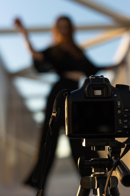 Ritratto verticale di un'insegnante di danza irriconoscibile che si filma con una fotocamera professionale per strada per insegnare lezioni di danza online messa a fuoco selettiva sulla fotocamera con treppiede