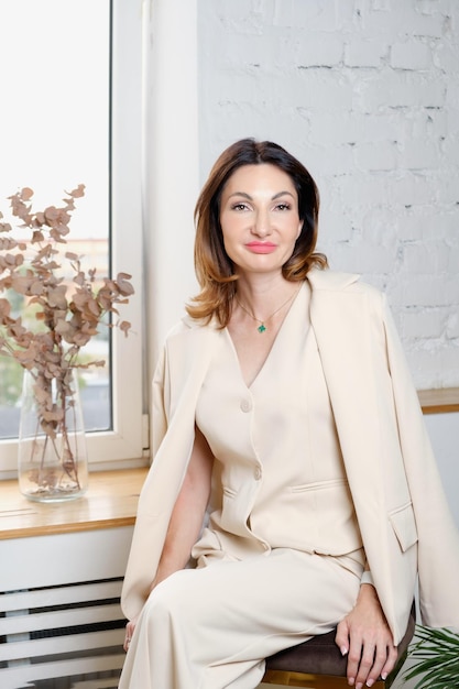Ritratto verticale di una donna d'affari in un tailleur pantalone beige estivo
