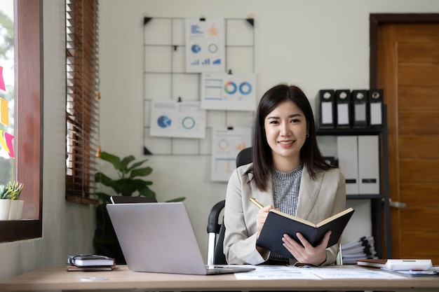 Riunione asiatica della donna di affari nell'ufficio che prende le note e usando un tablet in ufficio