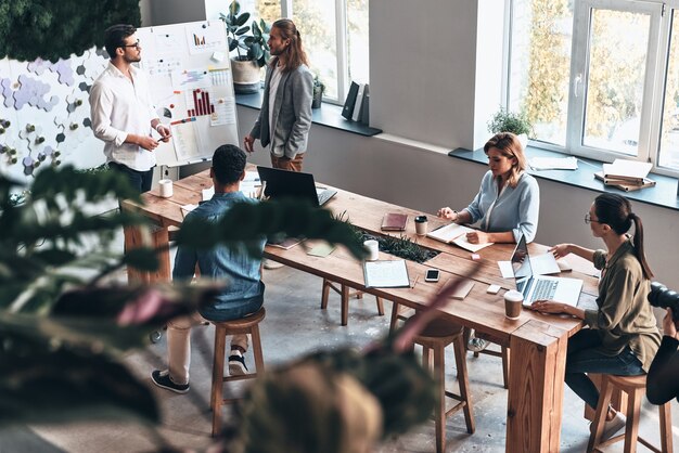 Riunione del personale. Vista dall'alto di due giovani uomini moderni che conducono una presentazione aziendale mentre si trovano nella sala riunioni