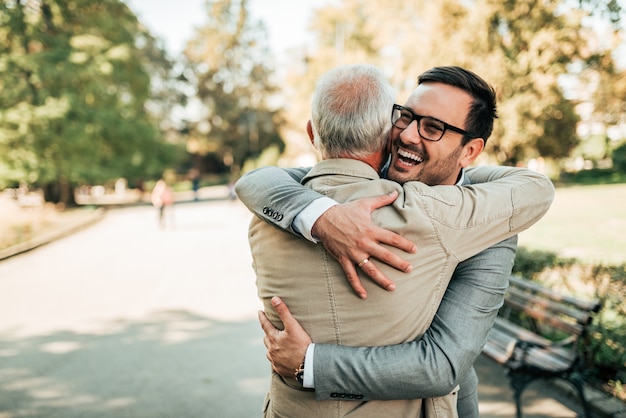 Riunione di famiglia. Padre e figlio che abbracciano all&#39;aperto.