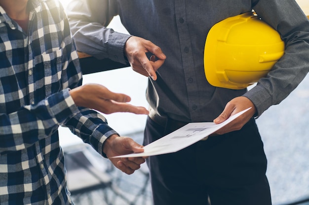 Riunione tra architetto e ingegnere Pianificazione di un nuovo progetto con attrezzature da costruzione sul tavolo Architetto ed ingegnere che lavorano con il progetto